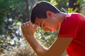 young man praying in nature